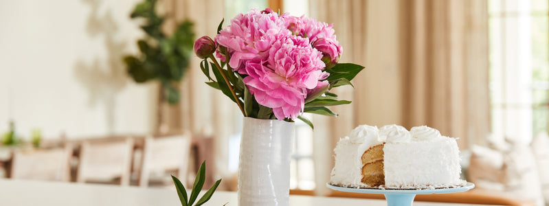 Bouquet of pink flowers in white vase with white birthday cake