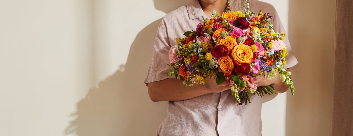 Person holding rainbow flower bouquet
