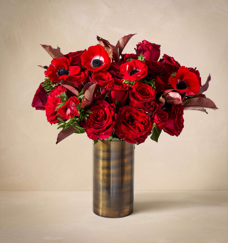 Bouquet of red flowers in a metallic vase on a beige background