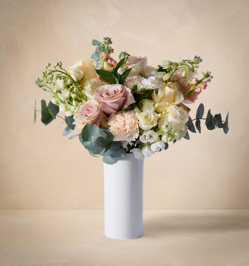 Bouquet of flowers in a white vase on a beige background