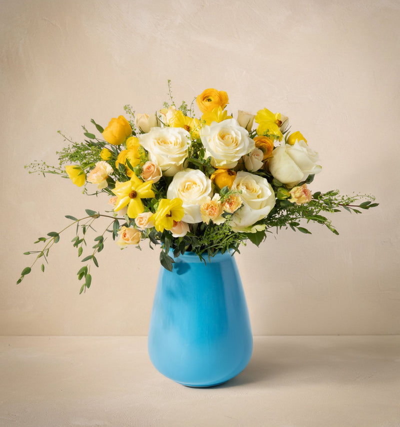 Bouquet of yellow and white flowers in a blue vase on a beige background
