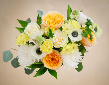 Bouquet of flowers with yellow, white, and orange colors on a beige background