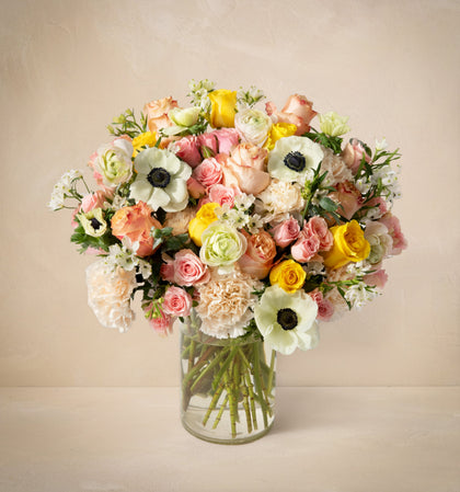 Bouquet of flowers in a clear vase on a beige background