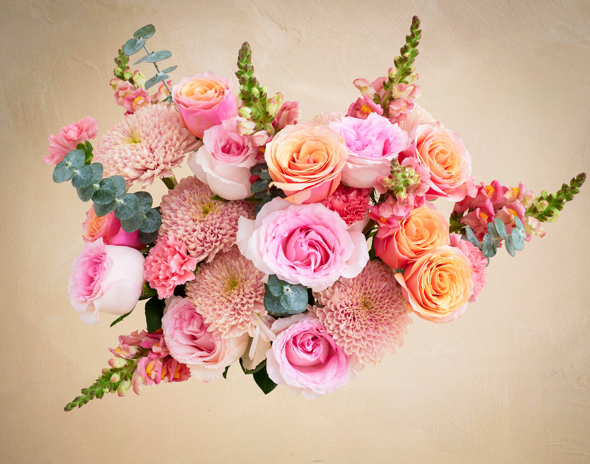 Bouquet of pink and orange flowers on a beige background