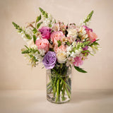 Bouquet of colorful flowers in a clear vase on a beige background