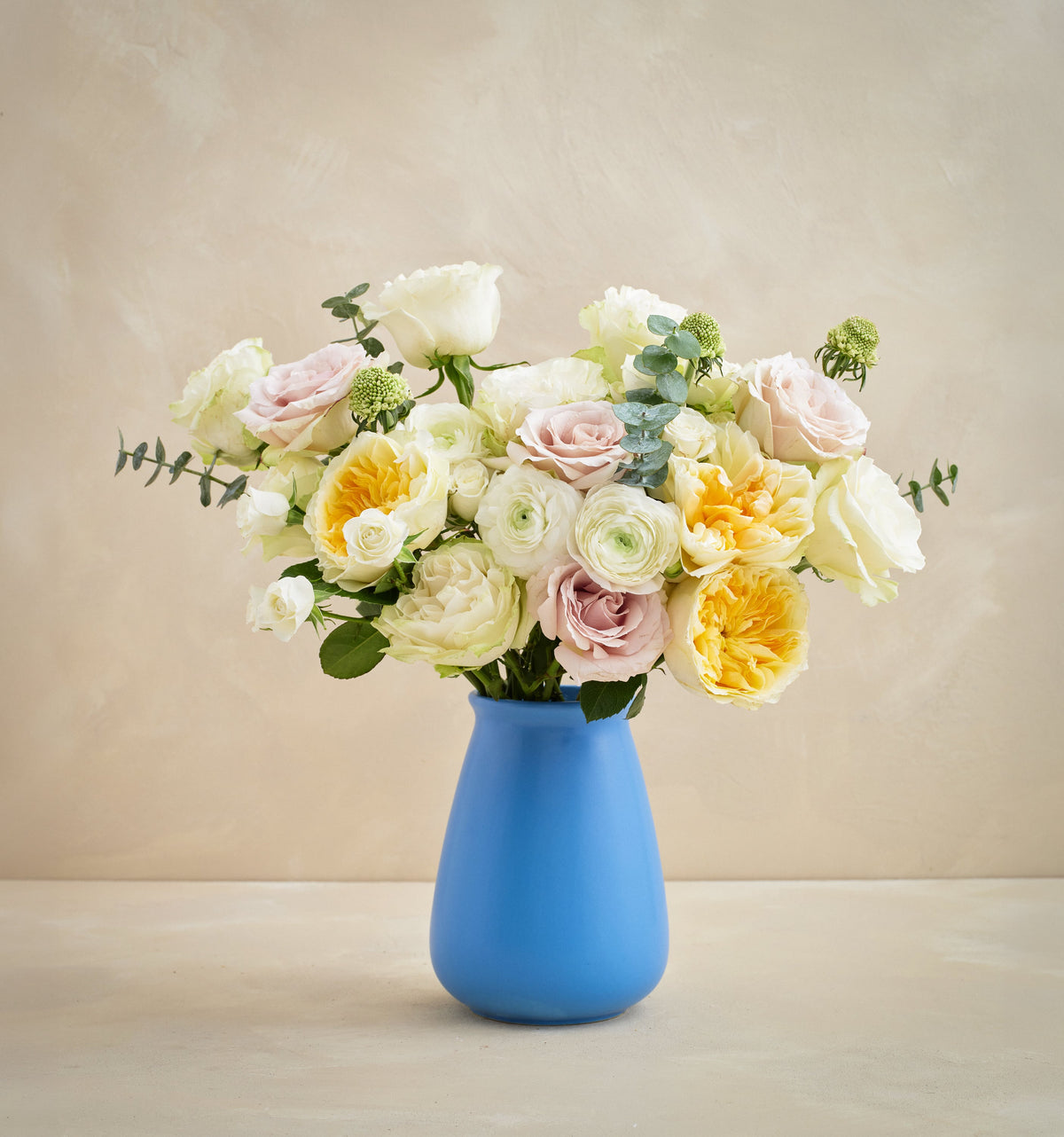 Bouquet of flowers in a blue vase on a beige background