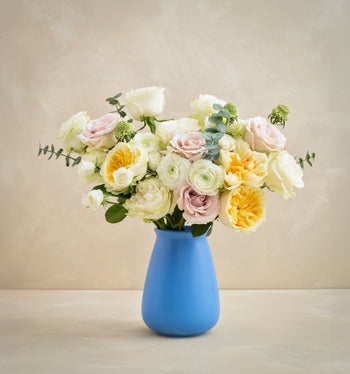 Bouquet of flowers in a blue vase on a beige background