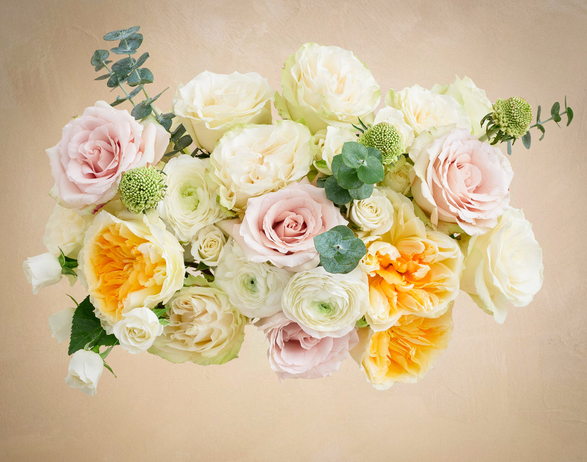 Bouquet of flowers with pink, white, and yellow roses on a beige background