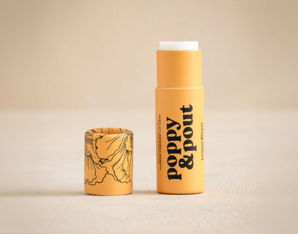 Two yellow lip balm tubes with 'Poppy & Pout' branding on a beige background