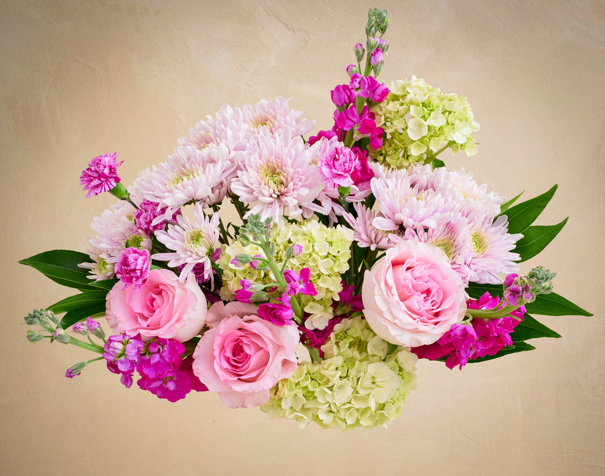 Bouquet of pink, green, and purple flowers on a beige background