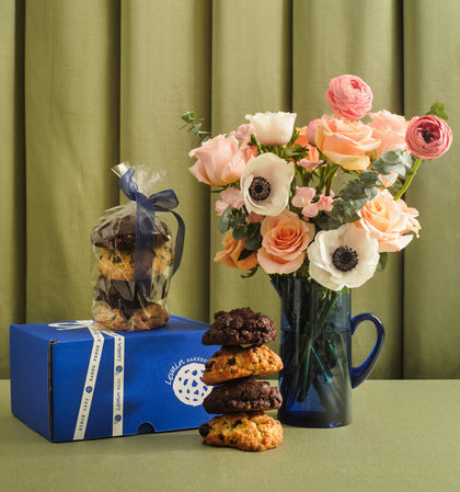Bouquet of flowers in a mug with cookies and a box on a green surface