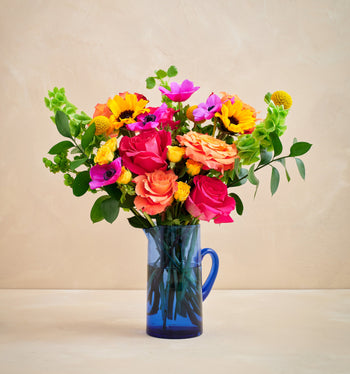 Colorful bouquet of flowers in a blue vase on a beige background
