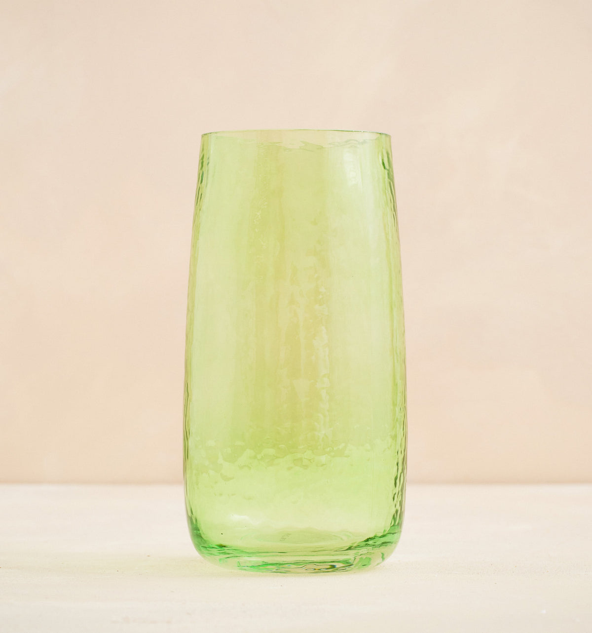 Green glass tumbler on a beige background