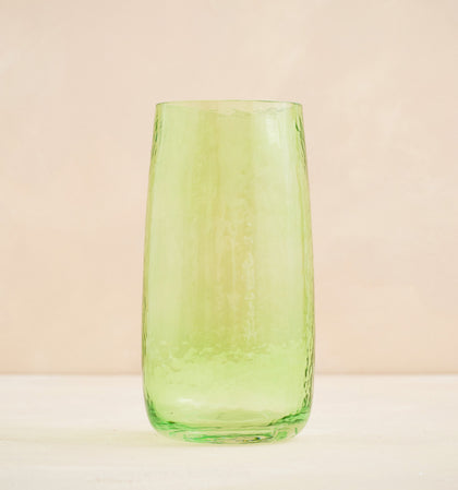 Green glass tumbler on a beige background