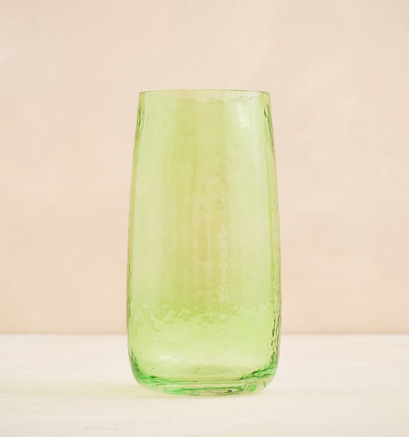 Green glass tumbler on a beige background