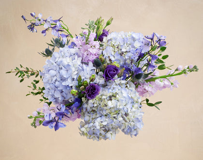 Bouquet of flowers with purple and white hydrangeas on a beige background