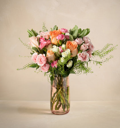 Bouquet of flowers in a clear vase on a beige background