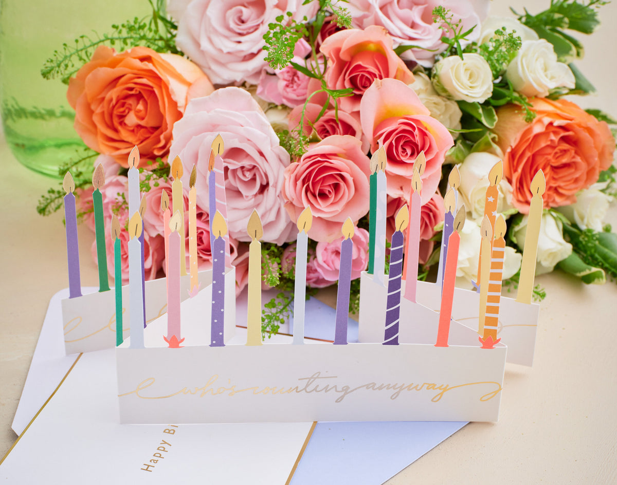 Floral arrangement with candles and a card on a light background