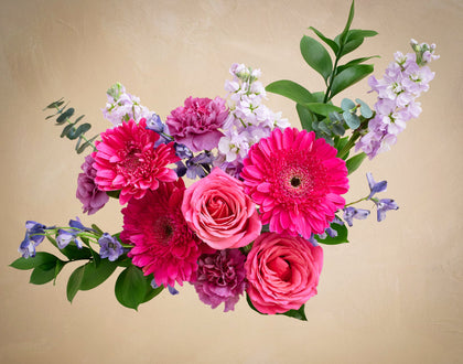 Bouquet of pink and purple flowers on a beige background