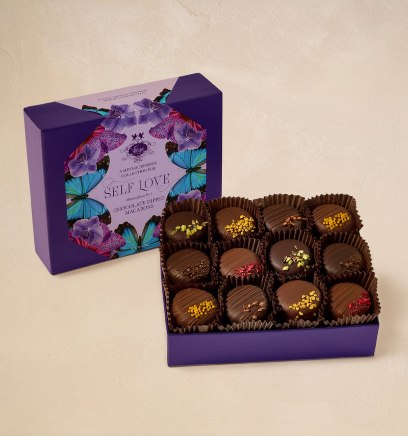 Box of chocolate macarons with a decorative purple box on a beige background