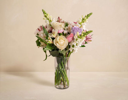 Bouquet of flowers in a clear vase on a beige background